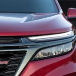 The driver side headlight and grille are shown on a red 2022 Chevy Equinox RS.