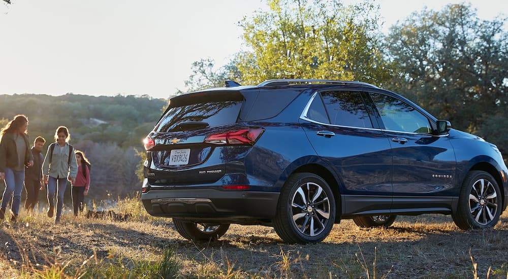 A blue 2022 Chevy Equinox is shown parked next to a hiking trail.