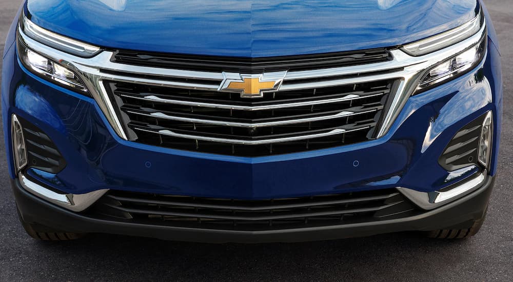 A close up of the grille of a blue 2022 Chevy Equinox shows the front headlights.