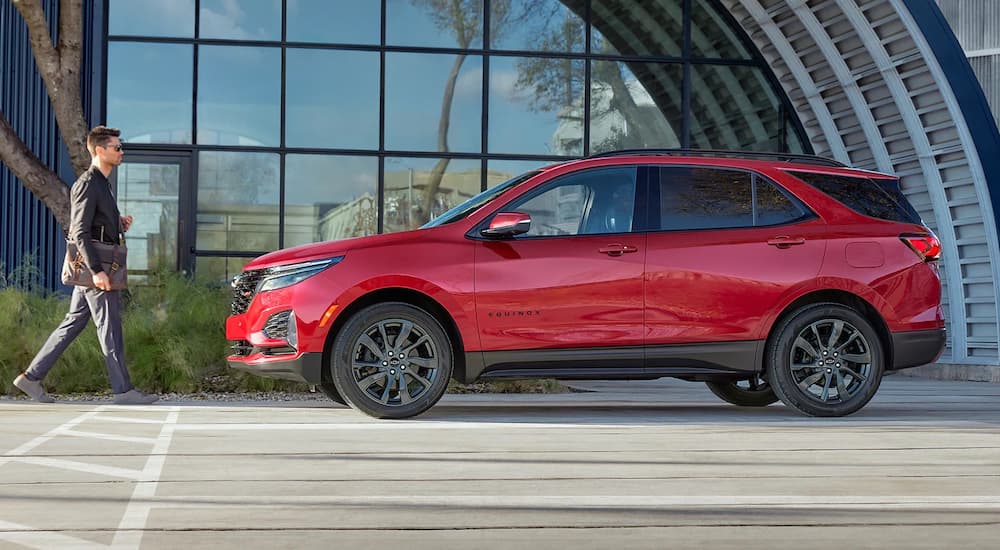 A red 2022 Chevy Equinox RS is shown parked on a street outside of a glass building after winning 2022 Chevy Equinox vs 2022 Hyundai Tucson showdown.