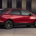 A red 2022 Chevy Equinox is shown from the side parked in a modern gallery after winning a 2022 Chevy Equinox vs 2022 Jeep Compass comparison.