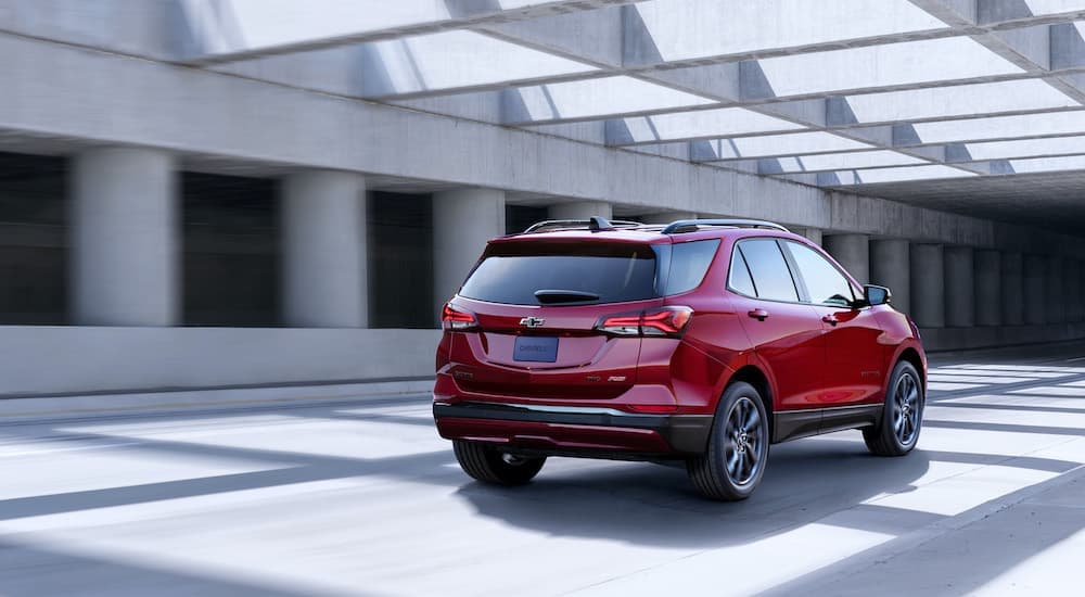 A red 2022 Chevy Equinox is shown from the rear driving past cement columns.