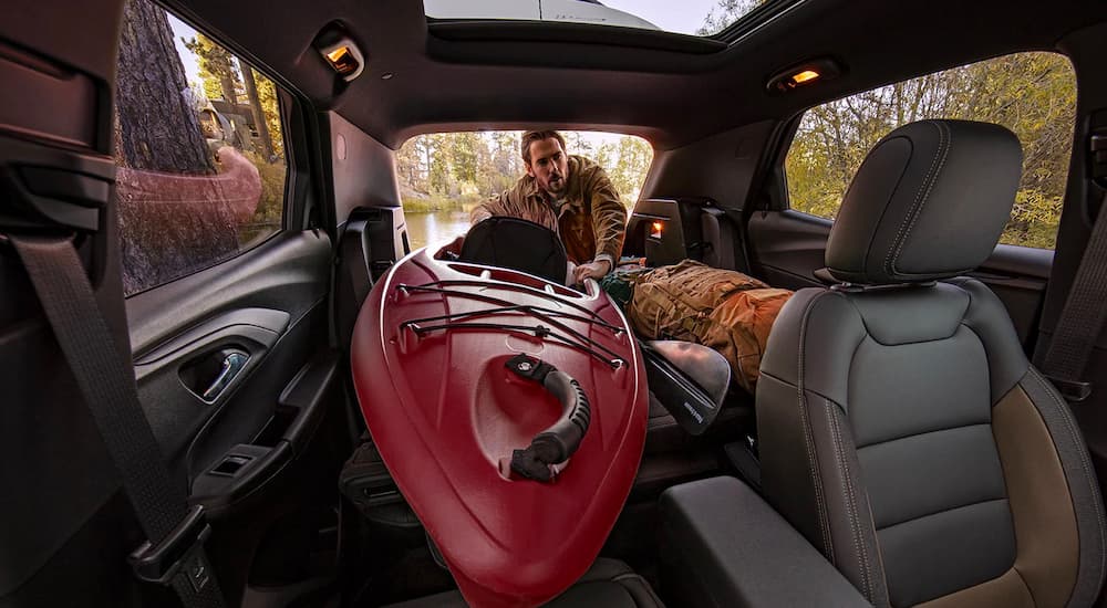 A man is shown storing a red kayak inside of his 2022 Chevy Trailblazer.
