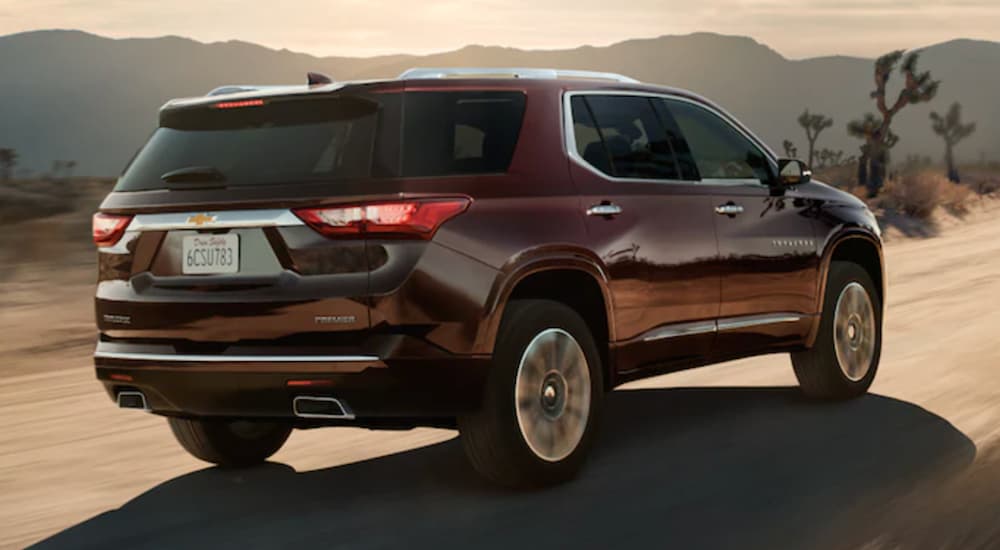 A maroon 2022 Chevy Traverse is shown from the rear driving on a desert road.