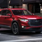 A red 2022 Chevy Traverse is shown in a city stopped at a red light.