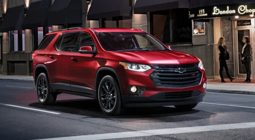 A red 2022 Chevy Traverse is shown in a city stopped at a red light.