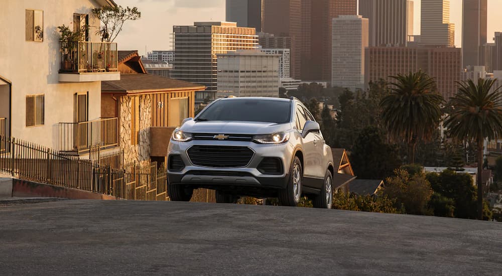 A silver 2022 Chevy Trax is shown driving through a city.
