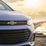 A close up shows the front of a silver 2022 Chevy Trax by the ocean.