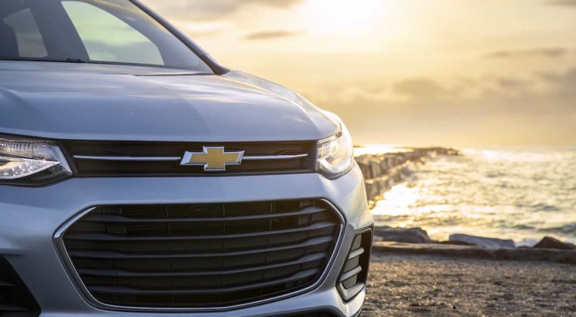 A close up shows the front of a silver 2022 Chevy Trax by the ocean.