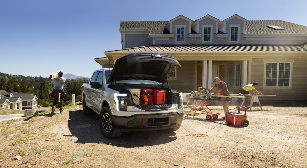 A grey 2022 Ford F-150 Lightning Pro is shown at a home construction site.