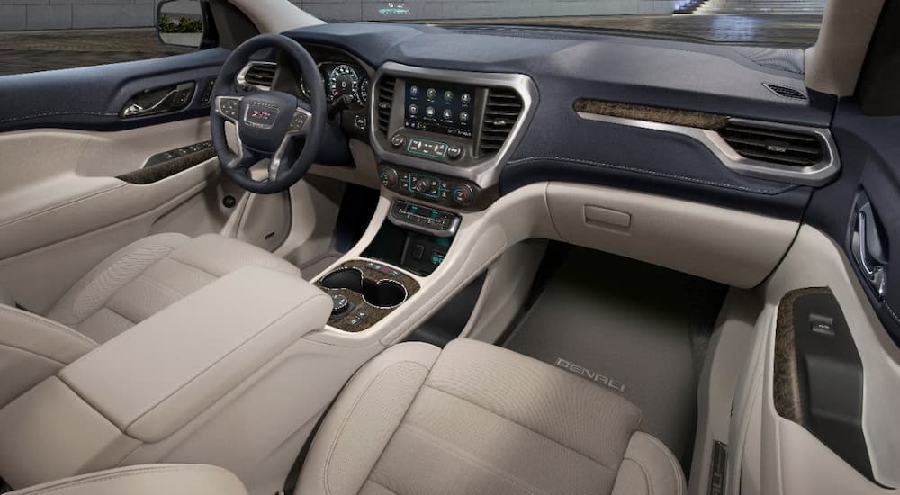 The tan and black leather interior of a 2022 GMC Acadia Denali shows the front seats, steering wheel, and center console.