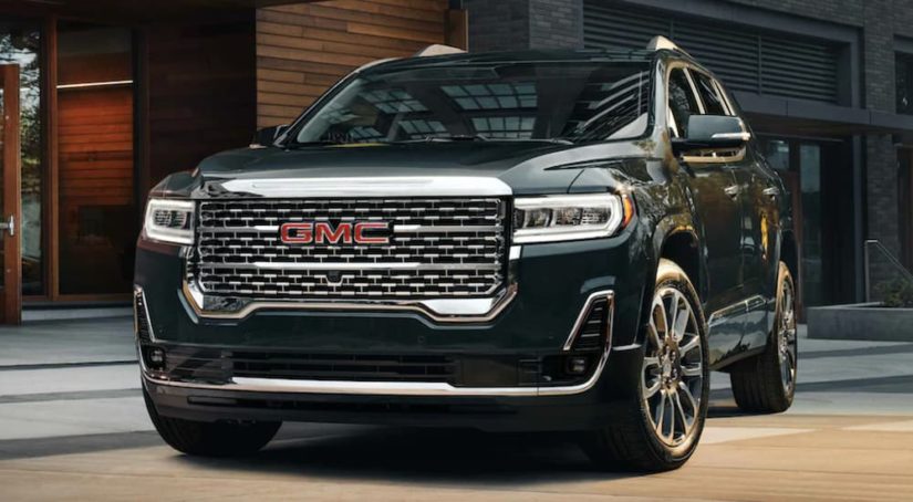 A black 2022 GMC Acadia is shown from the front parked in front of a modern building.