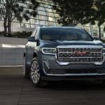 A grey 2022 GMC Acadia is shown parked outside of a modern building during a 2022 GMC Acadia vs 2022 Hyundai Santa Fe comparison.