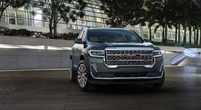 A grey 2022 GMC Acadia is shown parked outside of a modern building during a 2022 GMC Acadia vs 2022 Hyundai Santa Fe comparison.