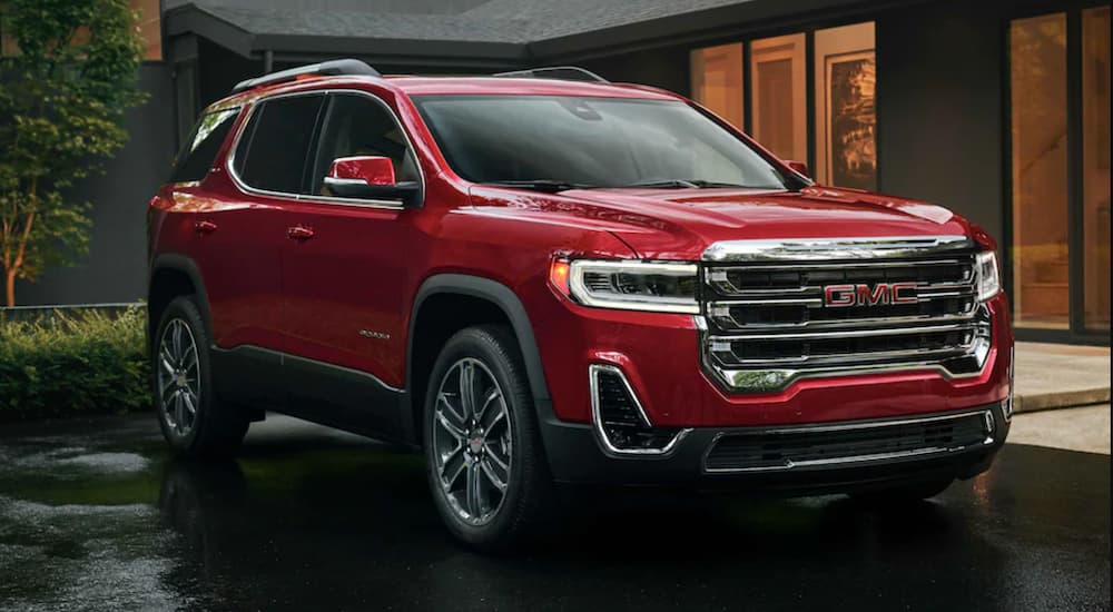 A red 2022 GMC Acadia is shown from the side parked in front of a modern building.