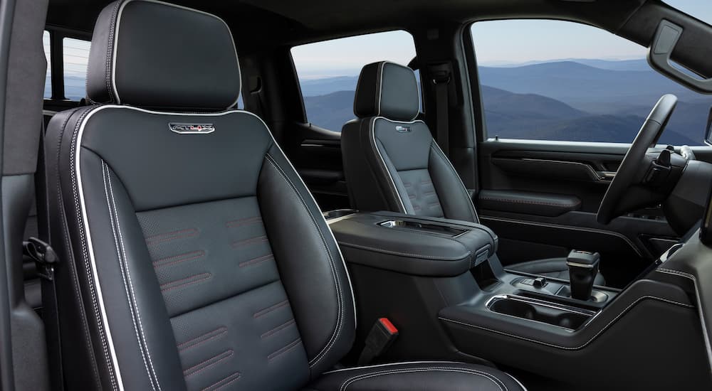 The black leather interior of a 2022 GMC Sierra 3500HD AT4X shows the front seats and center console.