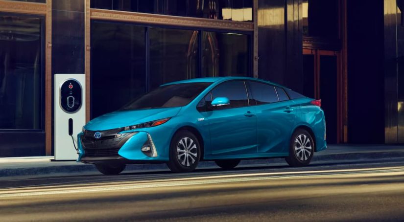 A blue 2022 Toyota Prius Prime Limited is shown at a charging station.
