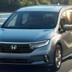 A silver 2022 Honda Odyssey Elite is shown from the front driving on an open road after winning a 2022 Honda Odyssey vs 2022 Chrysler Voyager comparison.