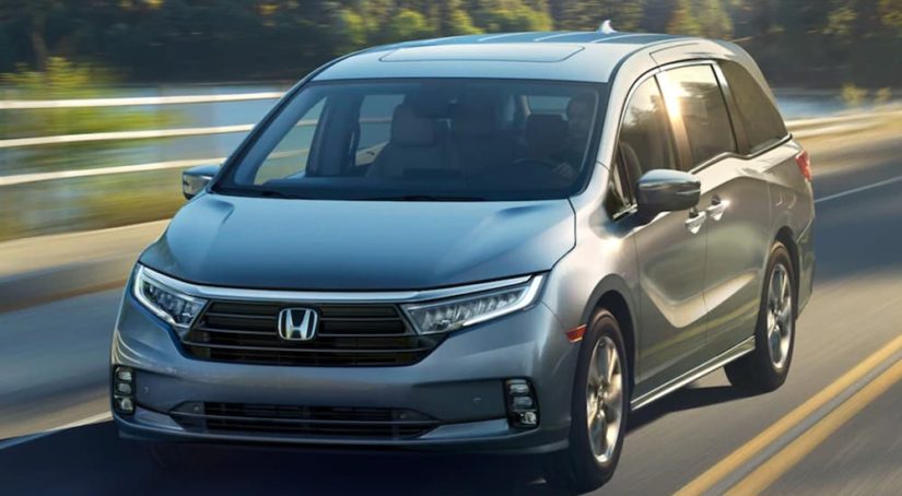 A silver 2022 Honda Odyssey Elite is shown from the front driving on an open road after winning a 2022 Honda Odyssey vs 2022 Chrysler Voyager comparison.