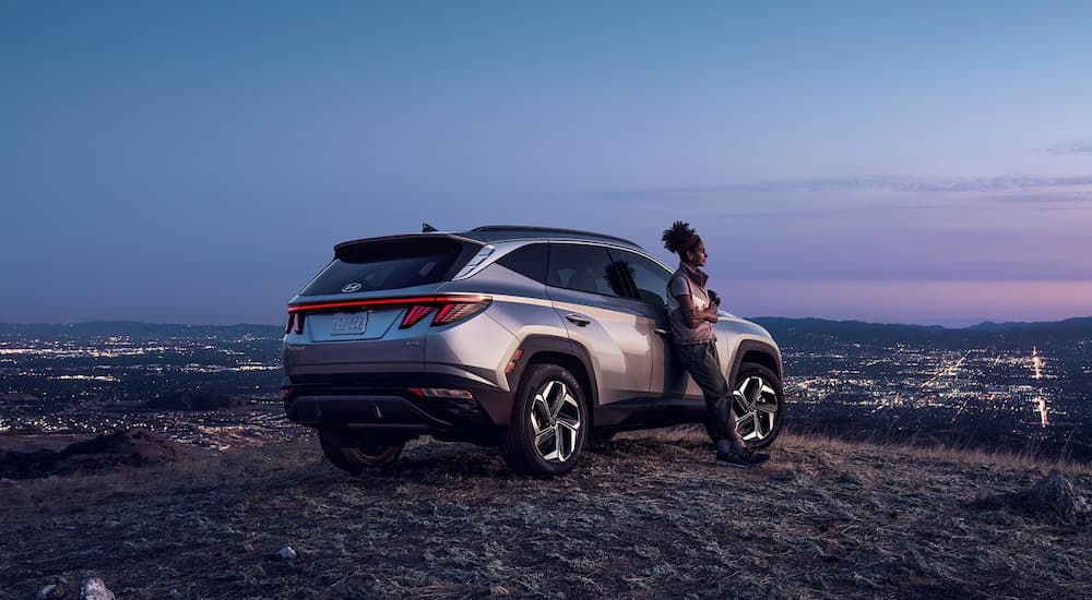 A silver 2022 Hyundai Tucson is shown on a hill overlooking a city.