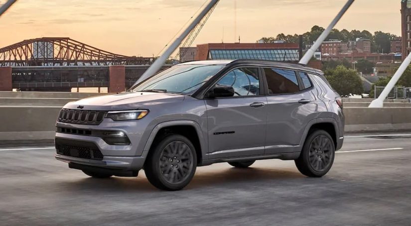 A grey 2022 Jeep Compass is shown driving on a bridge.