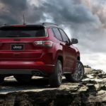 A red 2022 Jeep Compass is shown parked on a rock ledge.