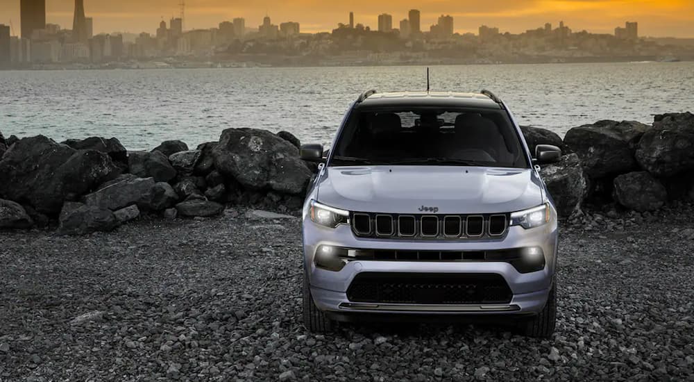 The front of a white 2022 Jeep Compass is shown parked in front of a bay.