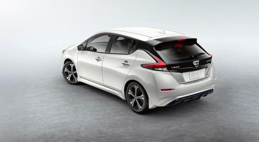 A white 2022 Nissan Leaf is shown from the rear parked on a concrete floor.