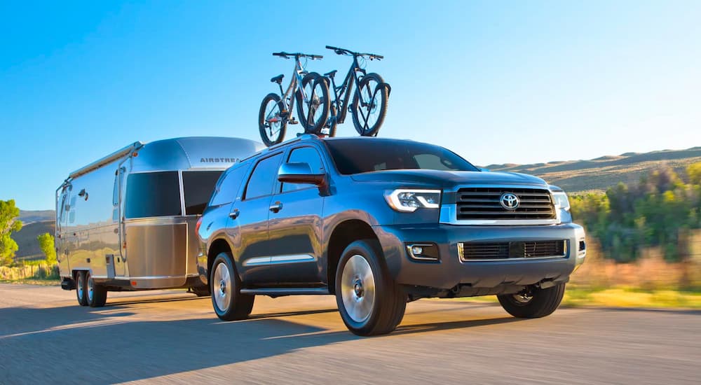 A silver 2022 Toyota Sequoia is showing towing an Airstream on a highway.