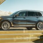 A blue 2022 BMW X7 SAV is shown from the side parked in front of a modern house.