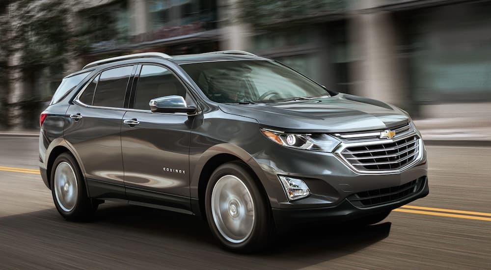 A grey 2019 Chevy Equinox is shown driving along a city street.