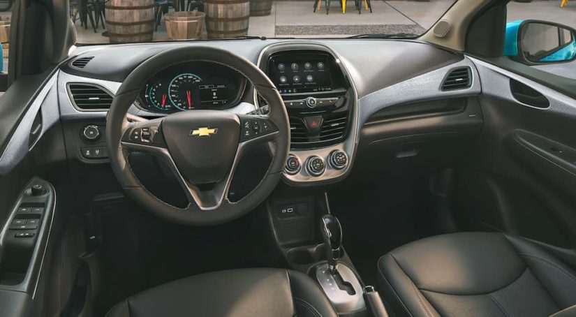 The black interior and dash of a 2021 Chevy Spark is shown from the back seat.