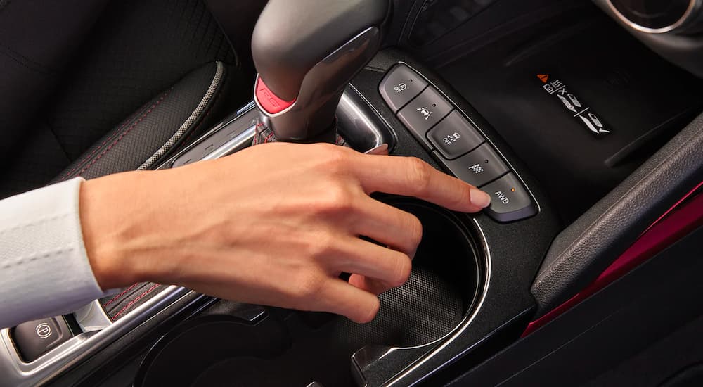 A hand is shown pressing the AWD drive mode button in a 2022 Chevy Trailblazer RS.