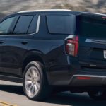 A black 2021 Chevy Tahoe is shown from the side driving on an open road.