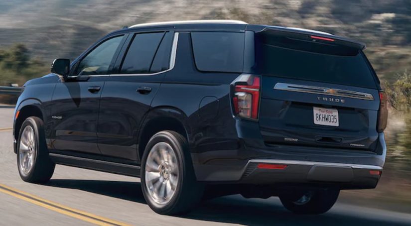 A black 2021 Chevy Tahoe is shown from the side driving on an open road.