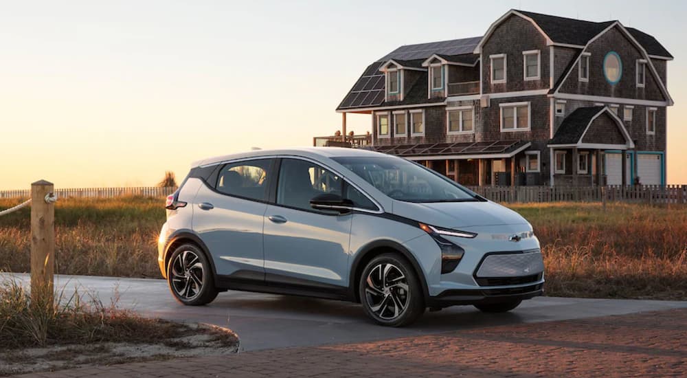 A blue 2022 Chevy Bolt EV is shown from the side parked in front of a beach house.