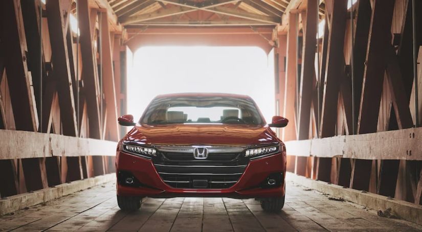 A red 2021 Honda Accord Touring 2.0T is shown form the front parked inside of a covered bridge after leaving a Honda Accord Dealership.