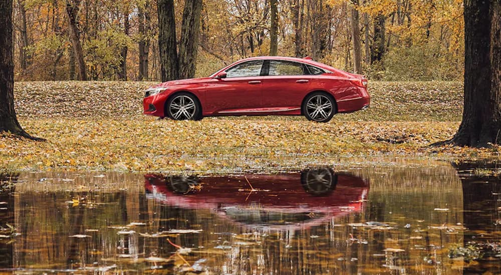 A red 2021 Honda Accord Touring 2.0T is shown from the side parked behind a lake.