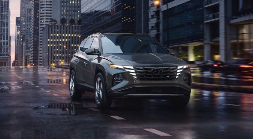 A grey 2022 Hyundai Tucson is shown driving on a city street at night.