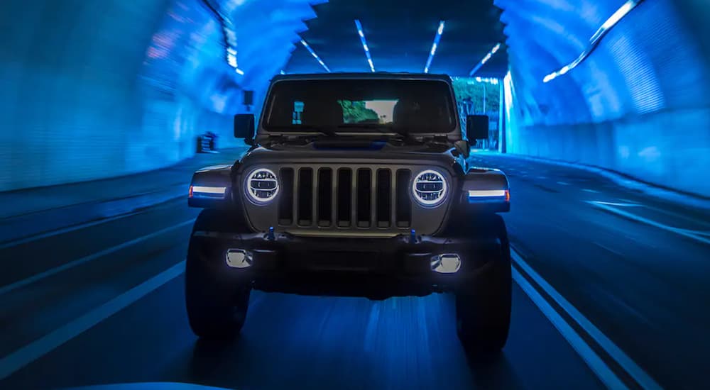 A silver 2021 Jeep Wrangler 4xe is shown from the front driving through a tunnel.