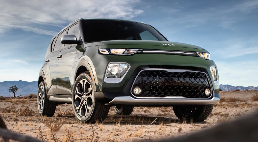 A green 2022 Kia Soul is shown from the front parked in a desert after leaving a Kia dealer.