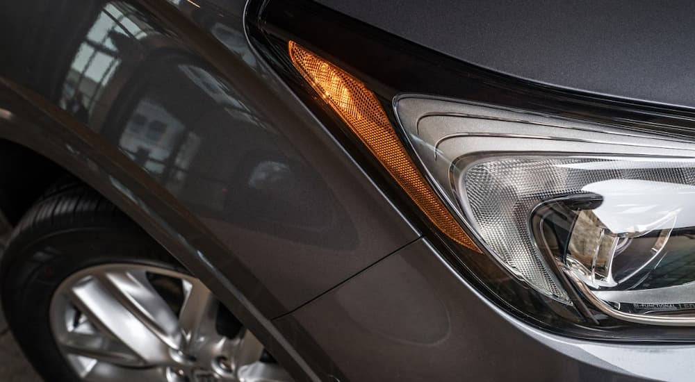 A close up of a 2019 Buick Envision shows the passenger side headlight and wheel.