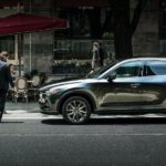 A grey 2020 Mazda CX-5 is shown from the side parked on a city street after visiting a used car dealer.