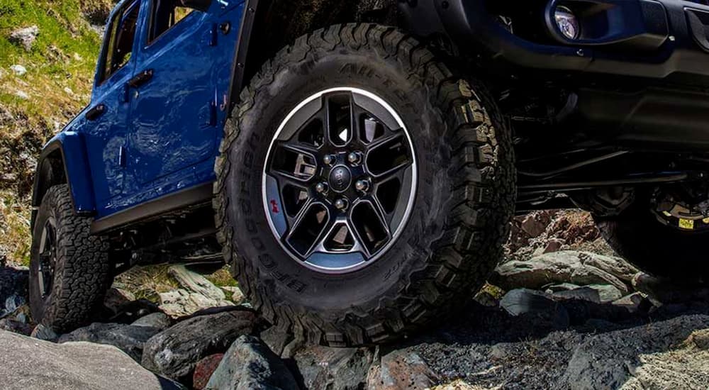 A close up of the passenger side tires are shown on a blue 2019 Jeep Wrangler.