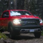A red 2019 Ram 1500 Rebel is shown from the front driving down a forest road.