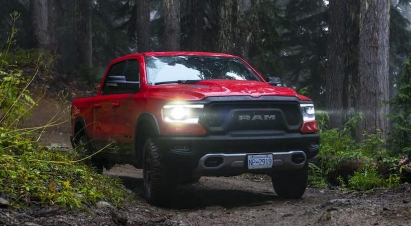 A red 2019 Ram 1500 Rebel is shown from the front driving down a forest road.