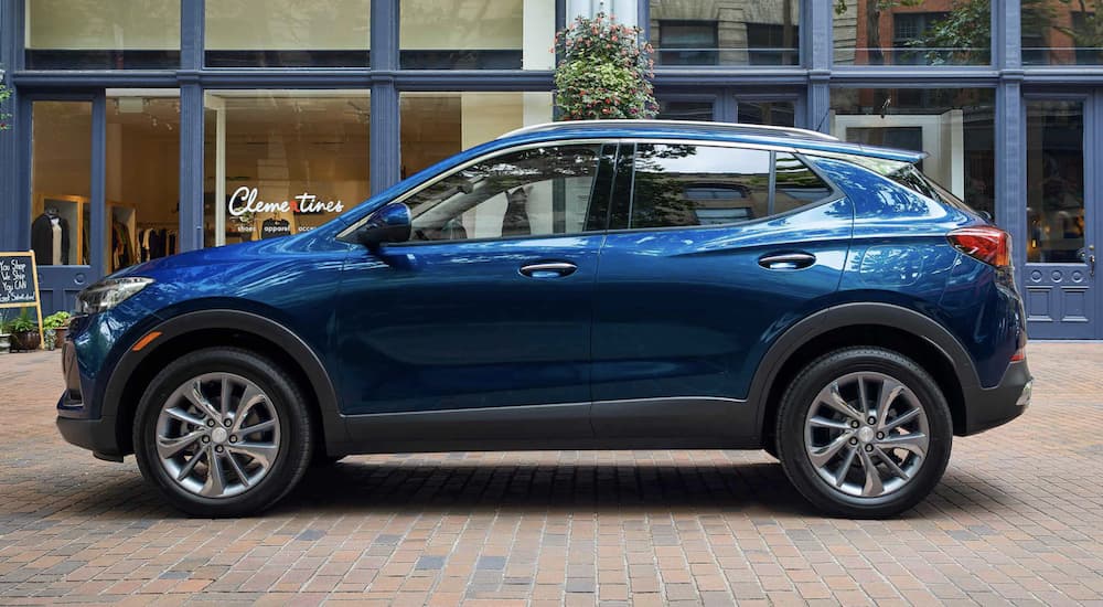A blue 2022 Buick Encore GX is shown from the side parked in front of a modern building.