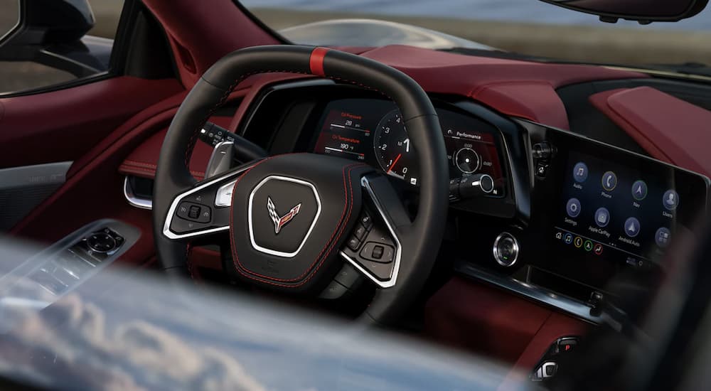 The black and red interior of a 2022 Chevy Corvette shows the steering wheel.