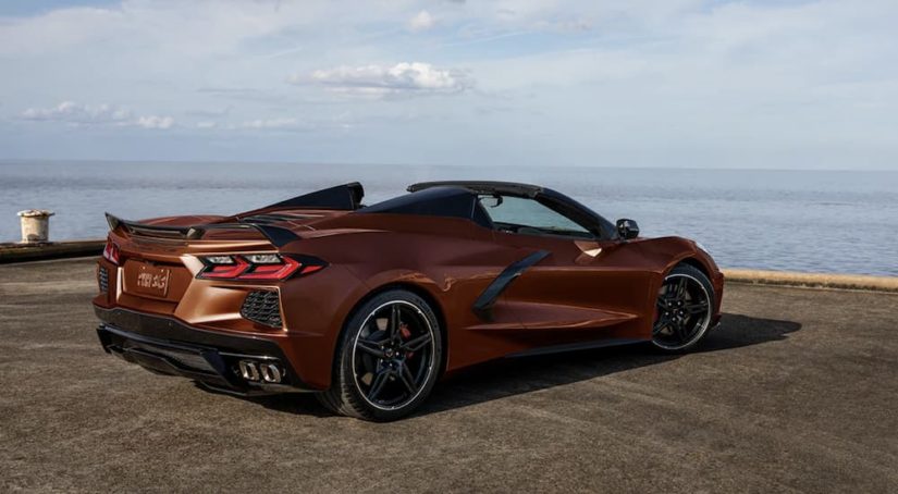 A bronze 2022 Chevy Corvette is shown from the side parked in front of an ocean.