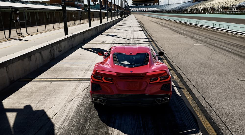 A red 2022 Chevy Corvette is shown from the rear driving on an open racetrack.